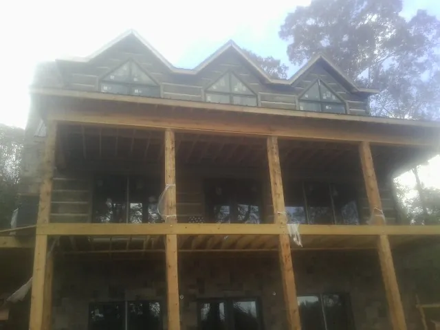 Dormers and porch framing on a large log home under construction — Roof Coating work by our crew in Newton